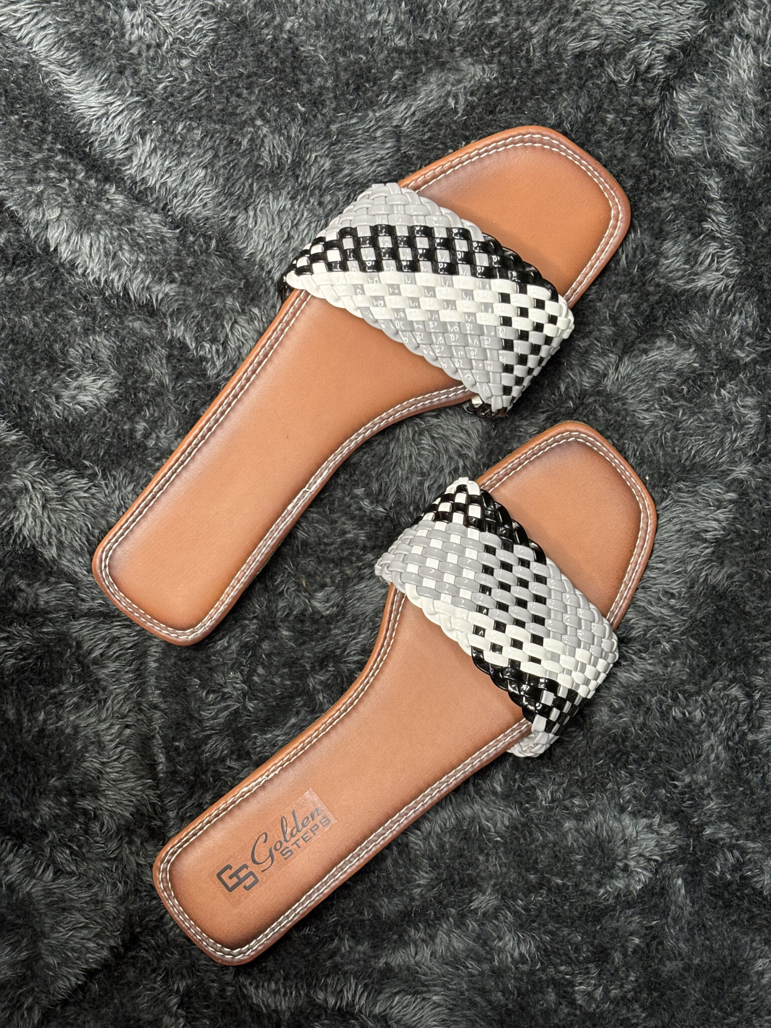 Handwoven leather slide sandals for women with black and white woven strap and durable brown leather sole.