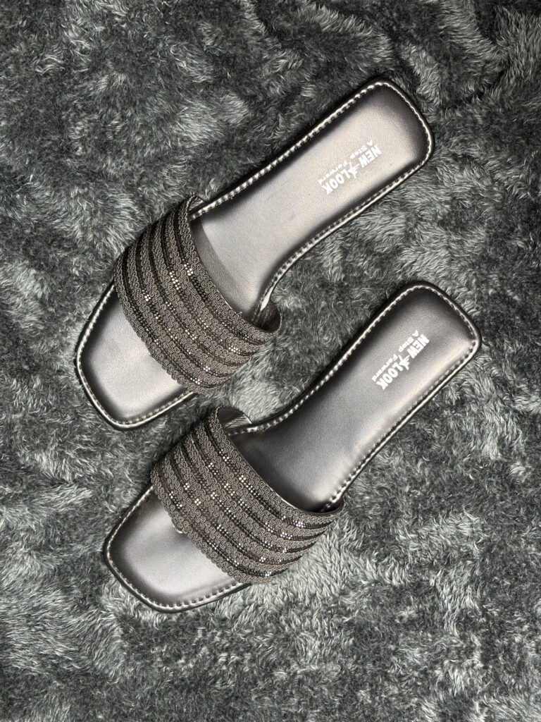 Glittery black flat sandals for women with a stylish metallic finish and slip-on design.